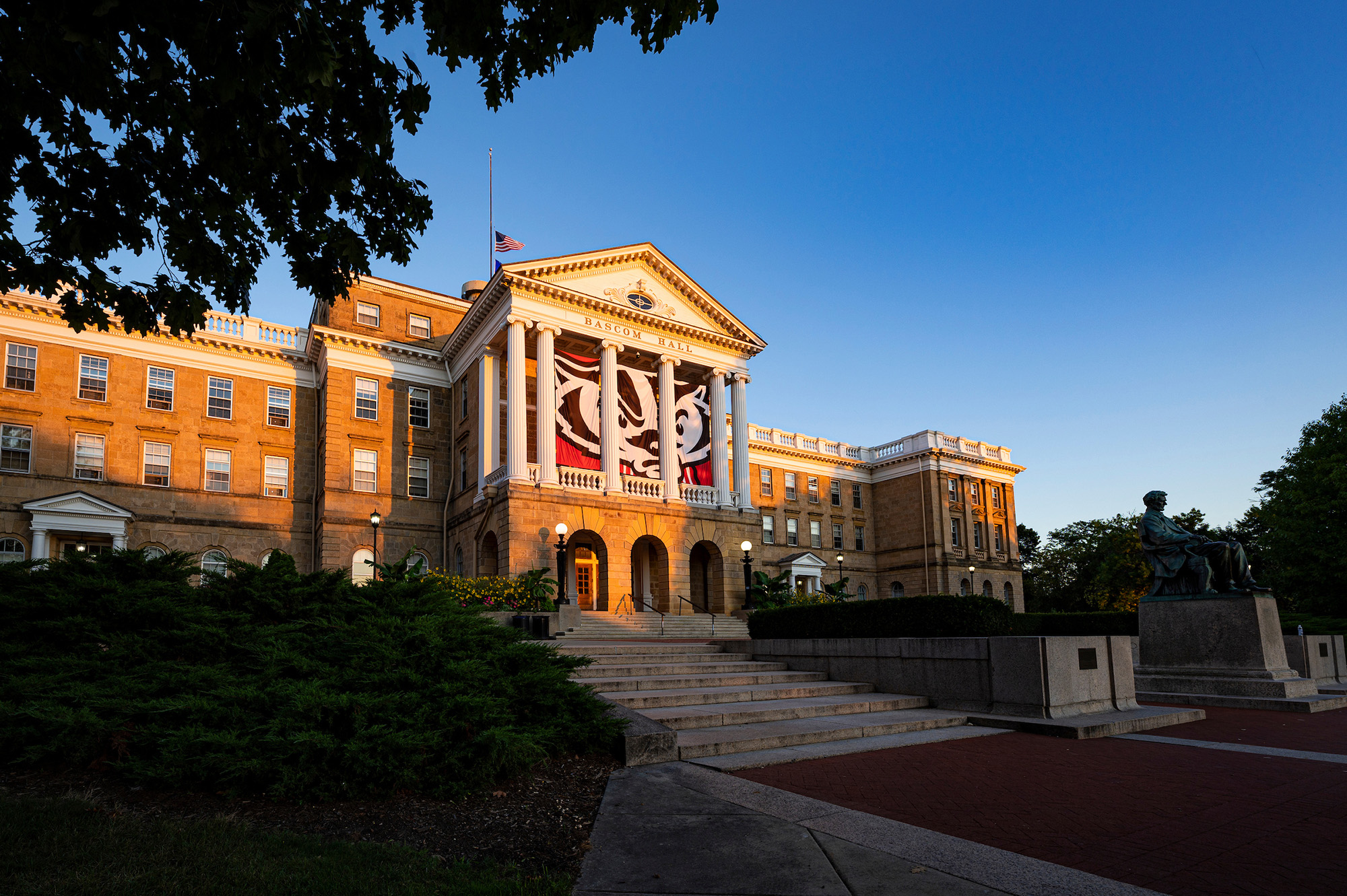 Bascom Hall at sunrise with large Bucky Badger banners hanging between the columns.