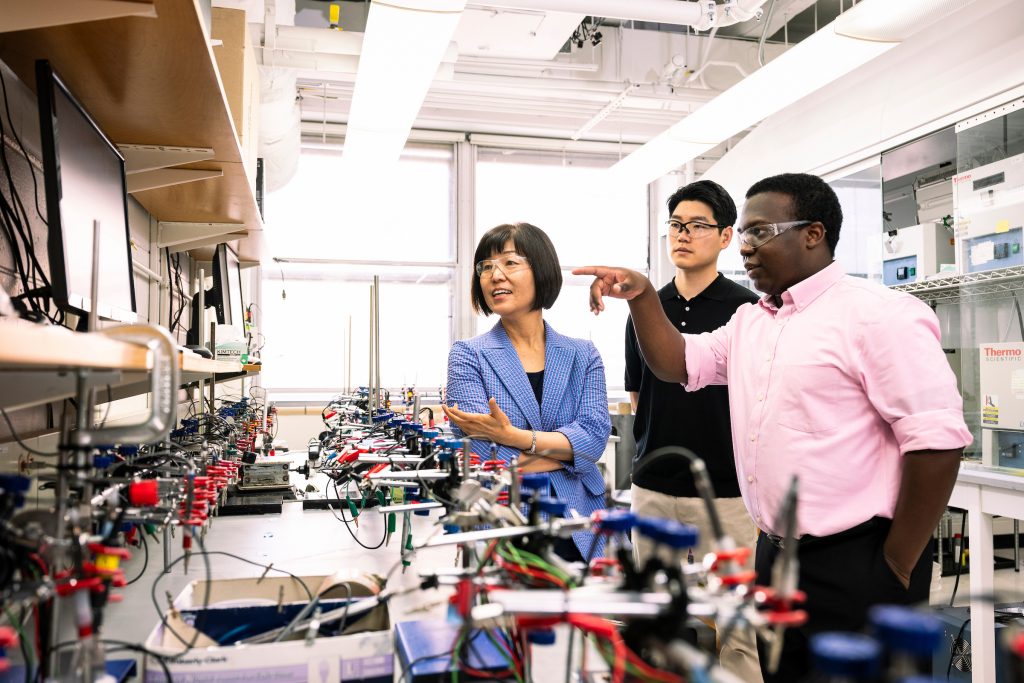 Group of researchers talking while looking at electronic equipment.