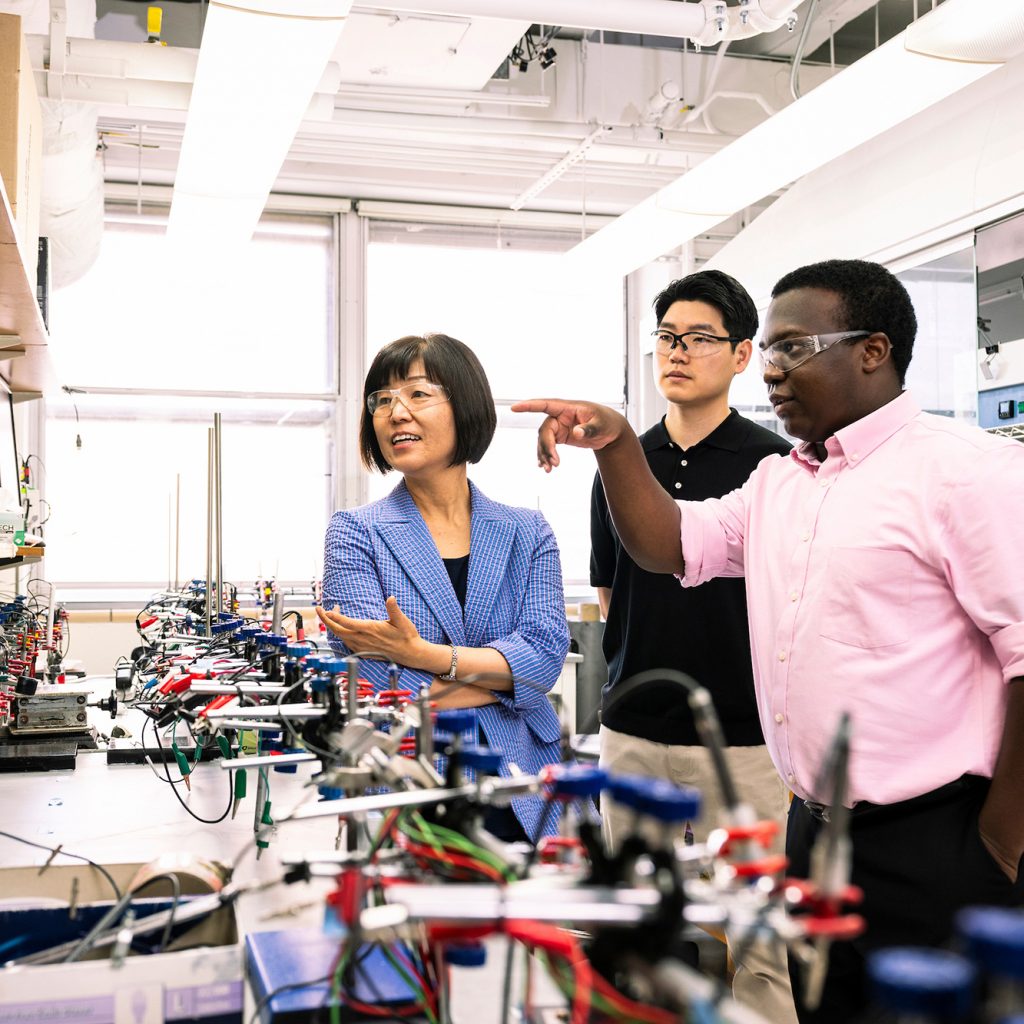 Group of researchers talking while looking at electronic equipment.