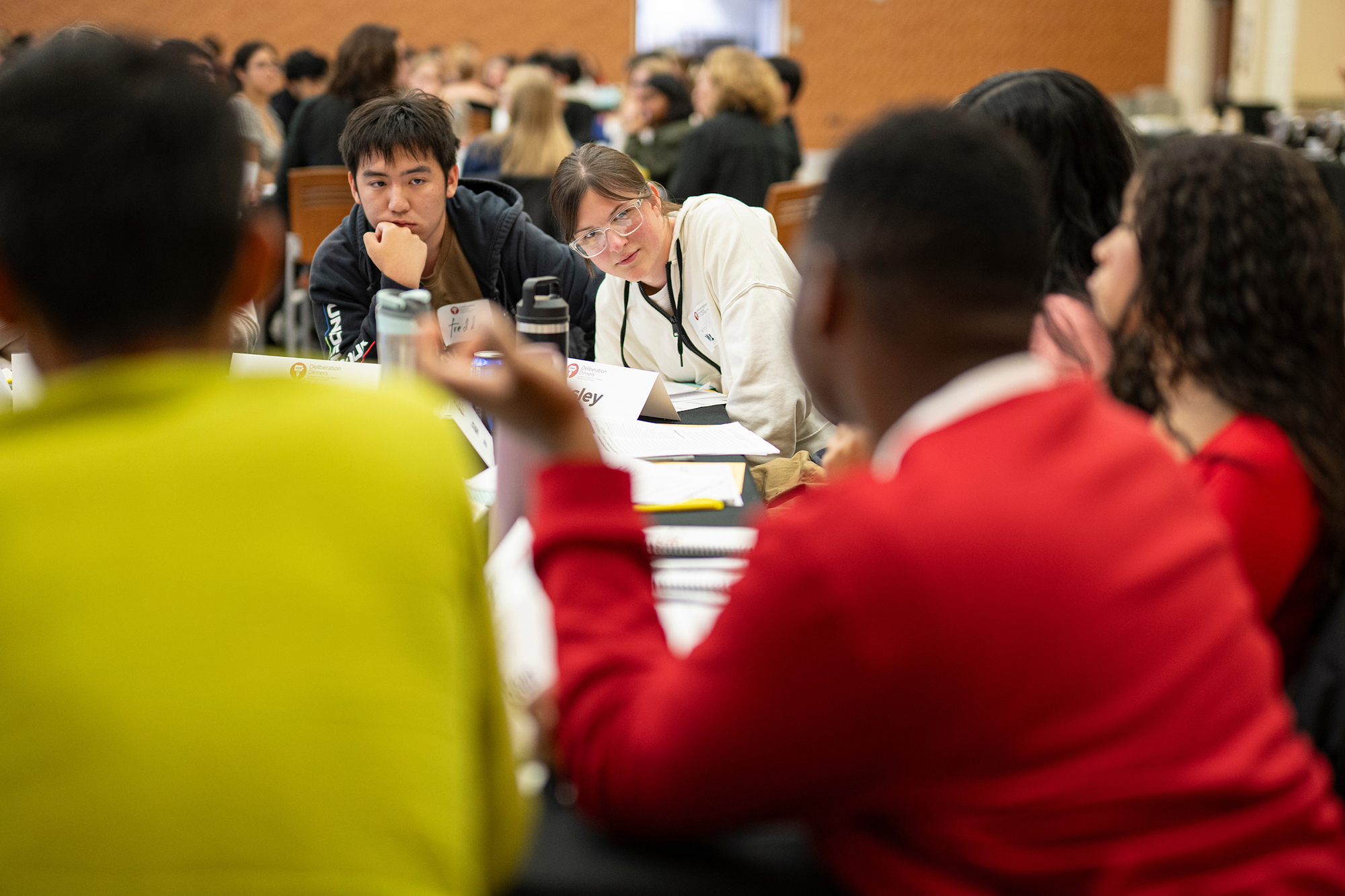 Group of people sitting around a table talking and listening intently.